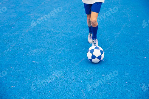 Preview: Little unrecognizable boy playing soccer of blue background
