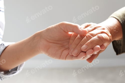 Preview: Helping hands on grey background, closeup. Elderly care concept