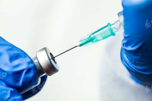 Preview: Detail closeup of syringe needle in ampoule vial,UK nurse taking injection shot