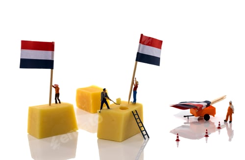 Preview: little people putting flags on dutch cheese