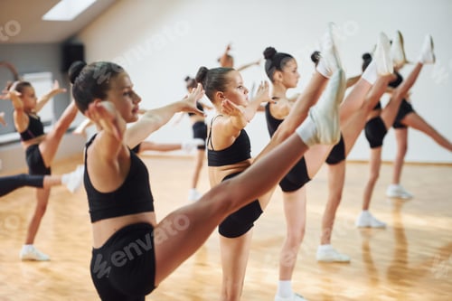 Preview: Side view of group of female kids that practicing athletic exercises together indoors