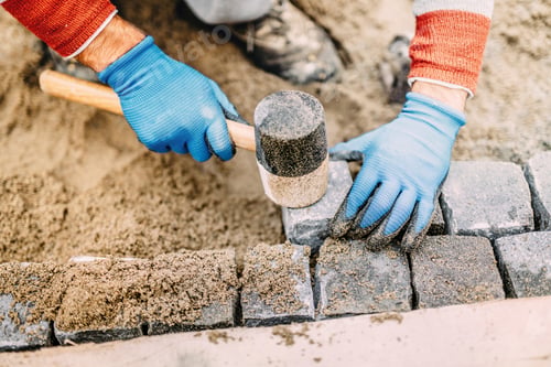 Preview: Construction worker placing stone tiles, cobblestone blocks in s