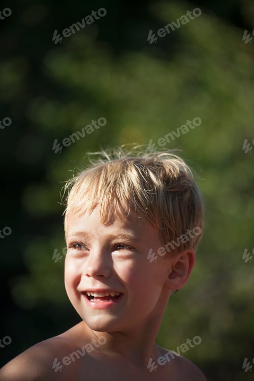 Preview: A child turning his head to look over his shoulders, smiling.