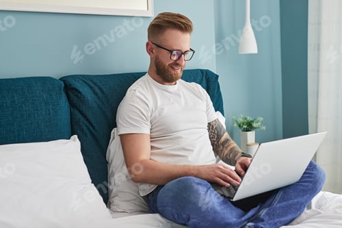 Man Working from Bed with Laptop