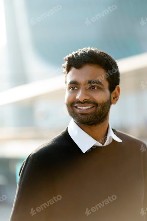 Preview: Smiling handsome Indian man looking away on the street