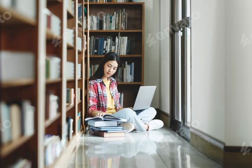 Preview: Young university student using laptop for online learning, searching and learning at library.