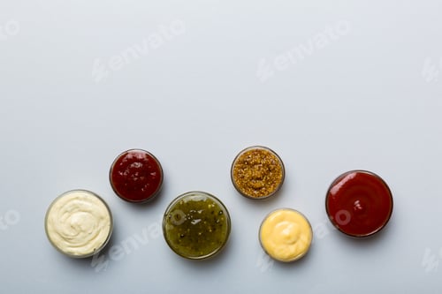 Preview: Different types of sauces in bowls on a colored Board . Top view. various sauces copy space