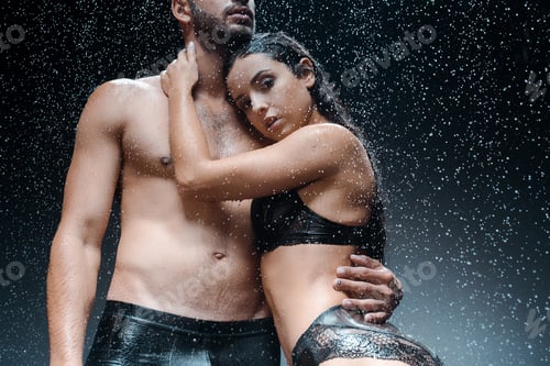 Preview: cropped view of wet shirtless man standing with girl under raindrops on black