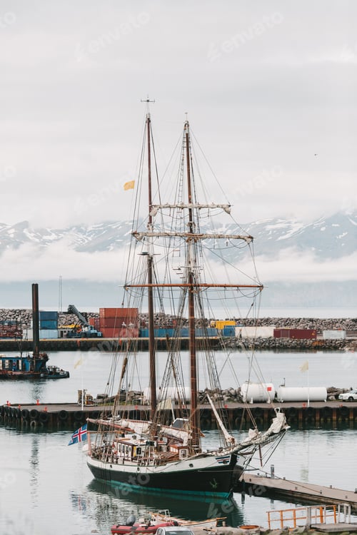 Preview: HUSAVIK, ICELAND - 20 JULY, 2016: yacht in harbour and beautiful snow-covered mountains on horizon