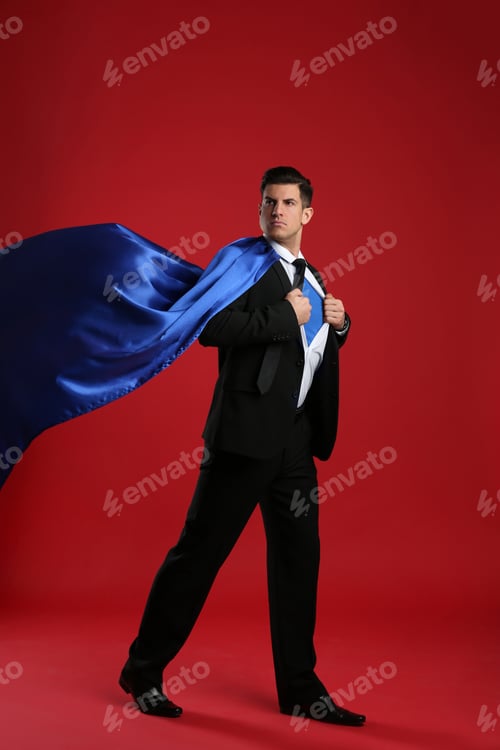 Preview: Businessman in superhero cape taking suit off on red background