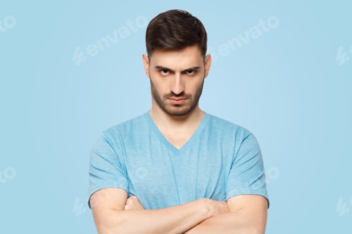 Preview: Young aggressive man standing with arms crossed and serious concentrated face