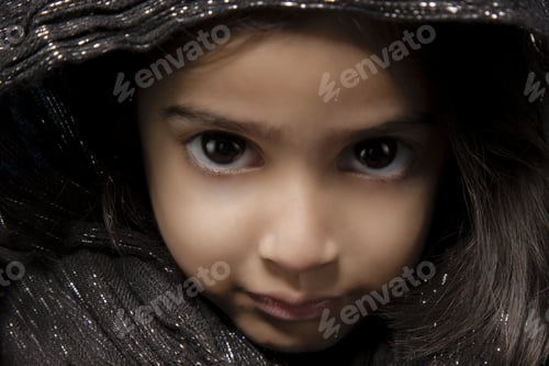 Preview: Closeup portrait of a cute young female with an innocent facial expression wearing a brown hood