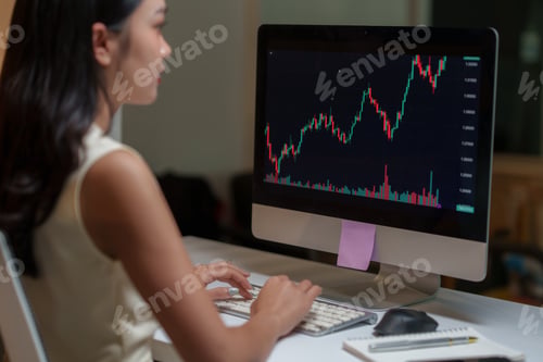 Preview: Businesswoman analyzing stock market data on computer at night