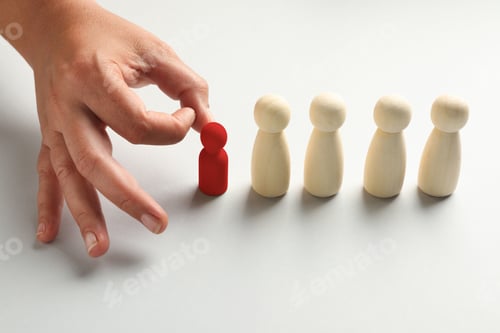 Preview: Dismissal. Woman choosing red figure among wooden ones at white table, closeup