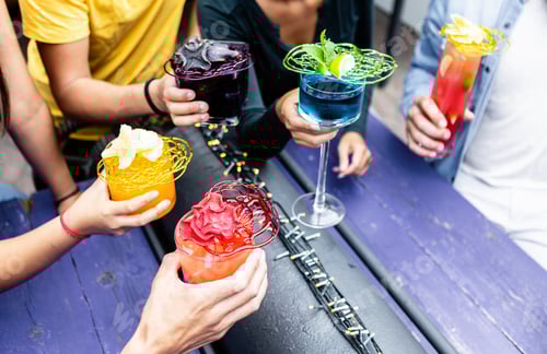 Preview: Group of friends cheering with trendy cocktails at rooftop pub