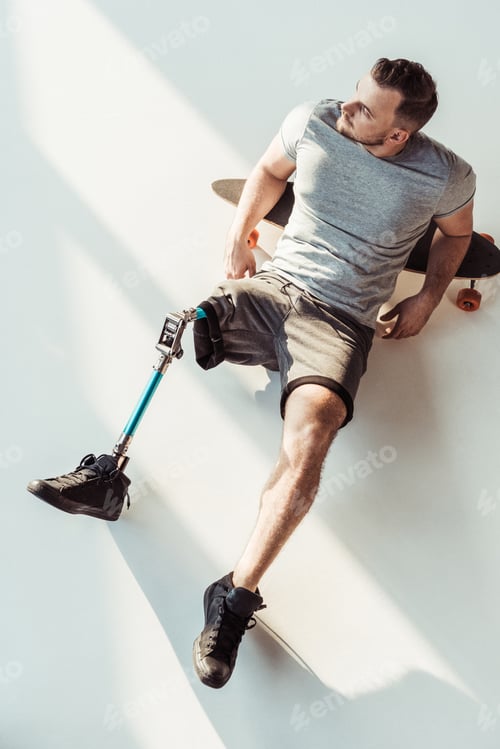Preview: overhead view of pensive man with leg prosthesis resting on skateboarding isolated on white
