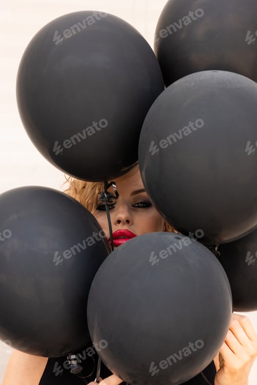 Preview: Beautiful woman of model appearance with dark balloons. Art shooting from unusual angles.
