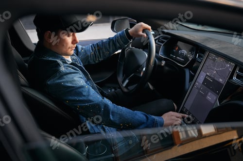 Preview: Guy driving car using touch screen on control panel.