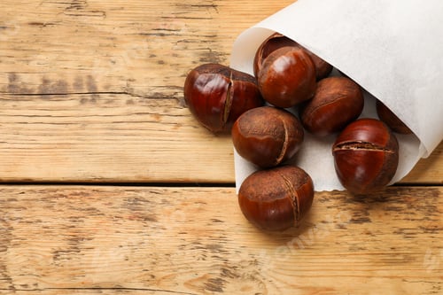 Preview: Fresh edible sweet chestnuts on wooden table, top view. Space for text