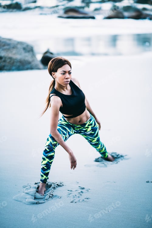 Preview: Young afro American woman doing stretches on beach
