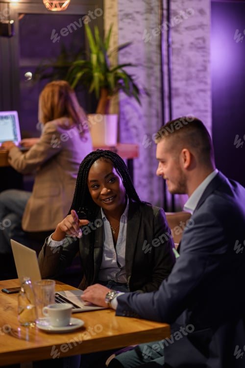 Preview: Two business people having a meeting in a cafe while using a laptop