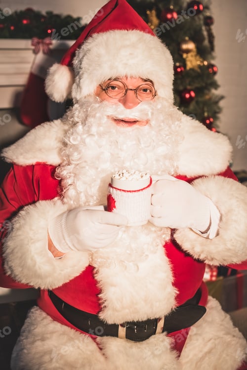 Preview: santa holding cup with hot drink and marshmallows and looking at camera