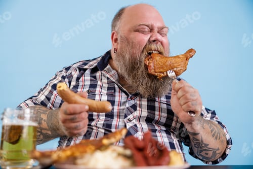 Preview: Expressive person with overweight eats chicken leg at table with greasy food