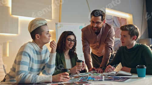 Preview: Creative manager presenting project at flip chart to colleagues drinking coffee.