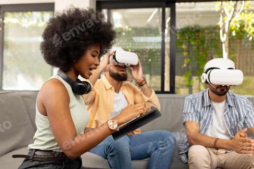 Preview: Using VR headsets, diverse friends exploring virtual reality while woman with tablet assists