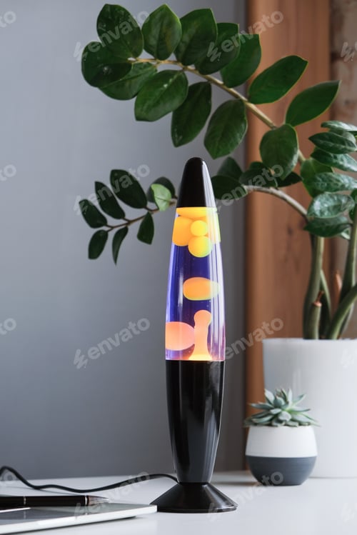 Preview: Yellow and blue lava lamp standing on working desk with plants in the office or home