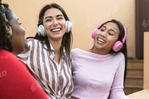 Preview: Happy multiracial friends having fun listening music with wireless headphones on house patio