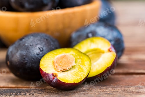 Preview: Fresh ripe plums and halves in wooden bowl close