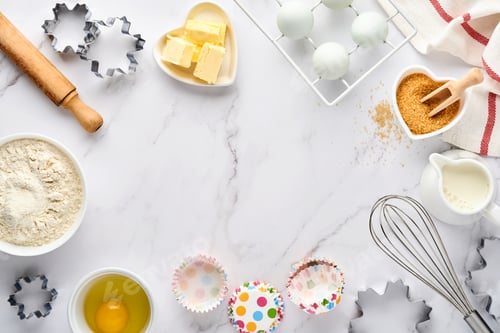 Preview: Baking background with flour, eggs, kitchen tools, utensils and cookie molds on white marble table.