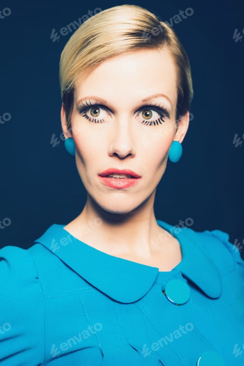 Preview: Serious Mature Blond Woman With An Elfin Face And Serious Expression Wearing A Stylish Blue Dress