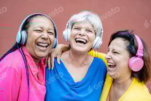 Preview: Multiracial senior women having fun listening music with headphones together - Technology trend