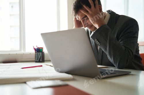 Preview: Stressed worker grabbing his head during work on laptop