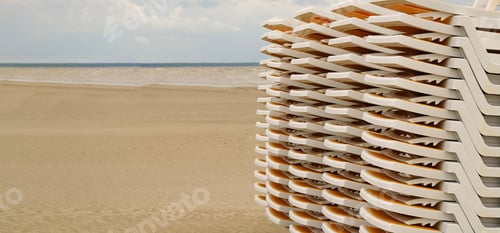Preview: Sun loungers stacked on top of each other stand in a row on the seashore on the sand.