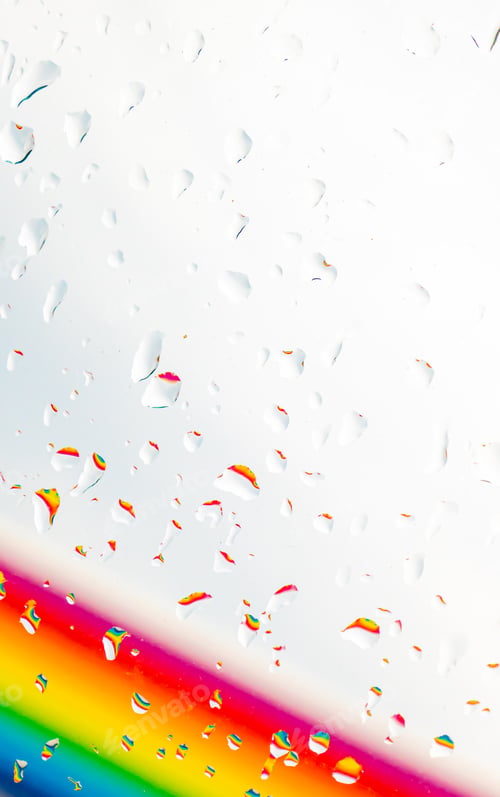 Preview: A rainbow behind a glass windows with water drops, Point of view, from behind the glass with drops.