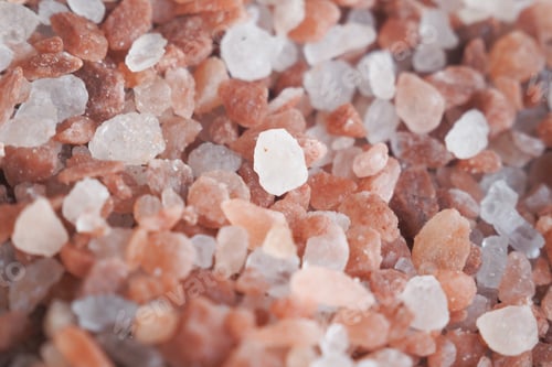 Preview: Raw whole dried pink Himalayan salt in a container on white