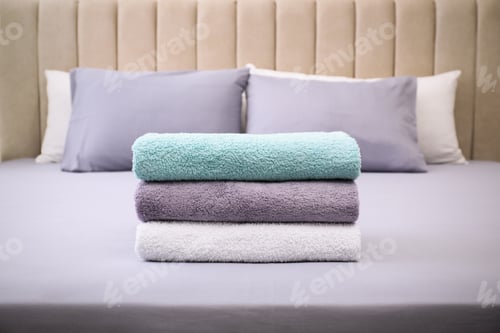 Preview: Stack of soft clean terry towels on bed