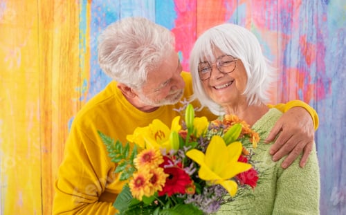 Preview: Attractive pleased elderly woman receives flowers as present for anniversary of Valentine day