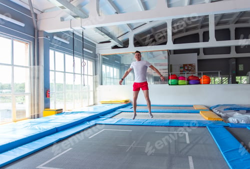 Preview: Fitness, fun, leisure and sport activity concept - Handsome happy man jumping on a trampoline