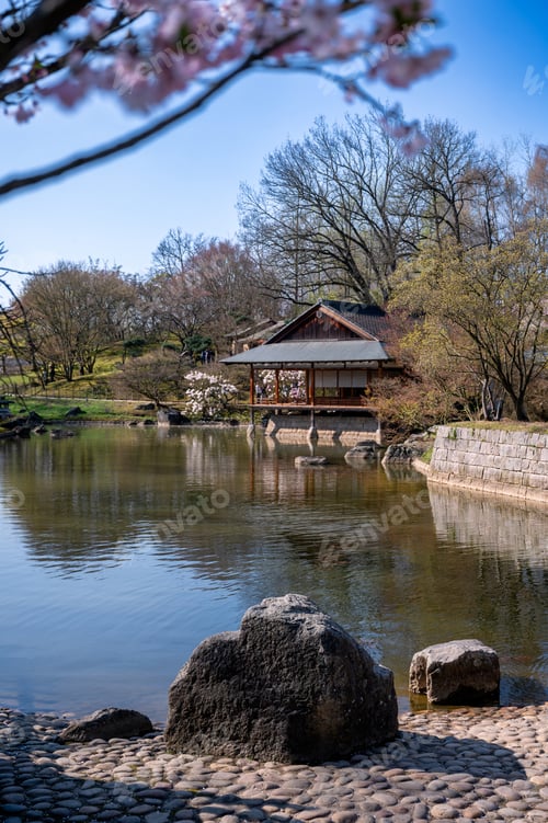 Preview: Japanese spring landscape scene. Calm waters reflecting pavilion surrounded by rocky shoreline