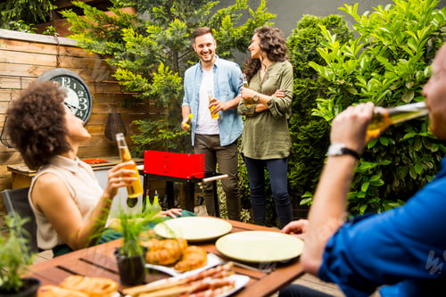 Preview: Happy friends grilling food and enjoying barbecue party outdoors