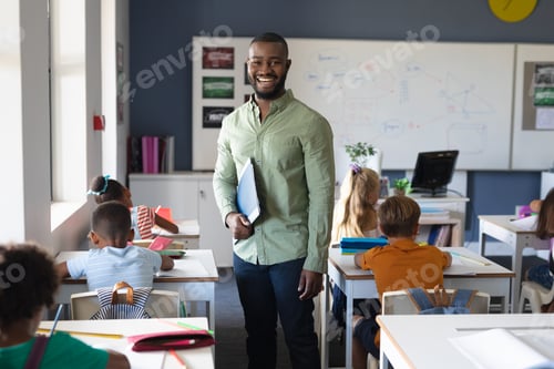 Preview: Portrait of smiling african american young male teacher standing by multiracial elementary students
