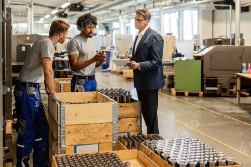 Preview: Two metal workers cooperating with quality control inspector in industrial facility.