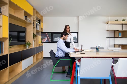 Preview: Young businesswoman and businessman working in modern office