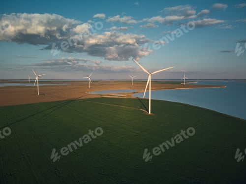 Preview: Aerial view of wind turbines and agriculture field near the sea at sunset