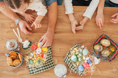 Preview: Top view of hands on the table. Happy family celebrating Easter holidays together