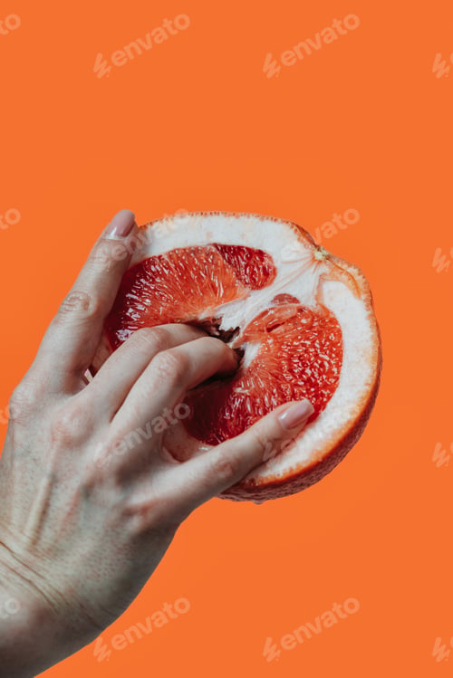 Preview: Image of a female hand with fingers inside a fresh grapefruit